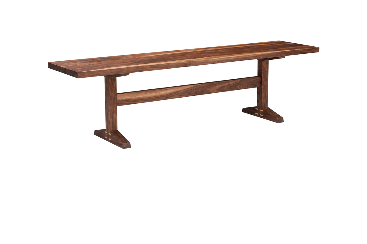 A rustic wooden bench with a dark brown finish, featuring a thick plank seat and angled trestle-style legs, isolated on a white background.