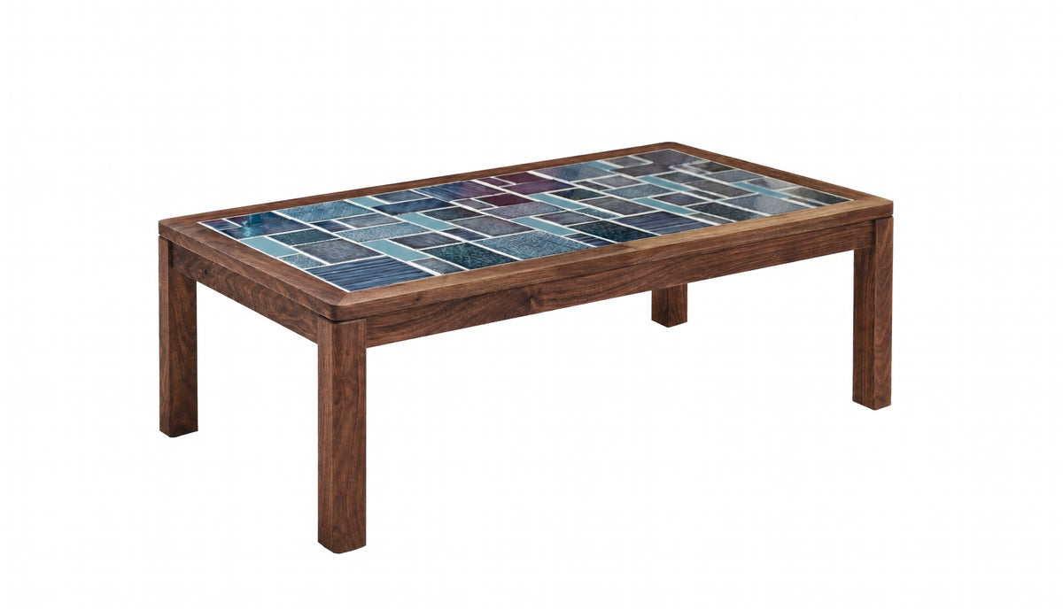 A rectangular wooden coffee table with a colorful mosaic tile top featuring shades of blue and teal, set against a plain white background.