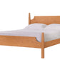 A light Cherry wood bed frame with a matching headboard and footboard, styled with white bedding and two pillows, isolated on a white background.