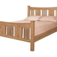 A traditional bed with slats and panels made with light Oak wood frame and headboard, dressed in white bedding and two white pillows, shown against a plain white background.
