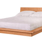 A modern platform bed with a light Cherry wood frame and headboard, dressed in white bedding and two white pillows, shown against a plain white background.