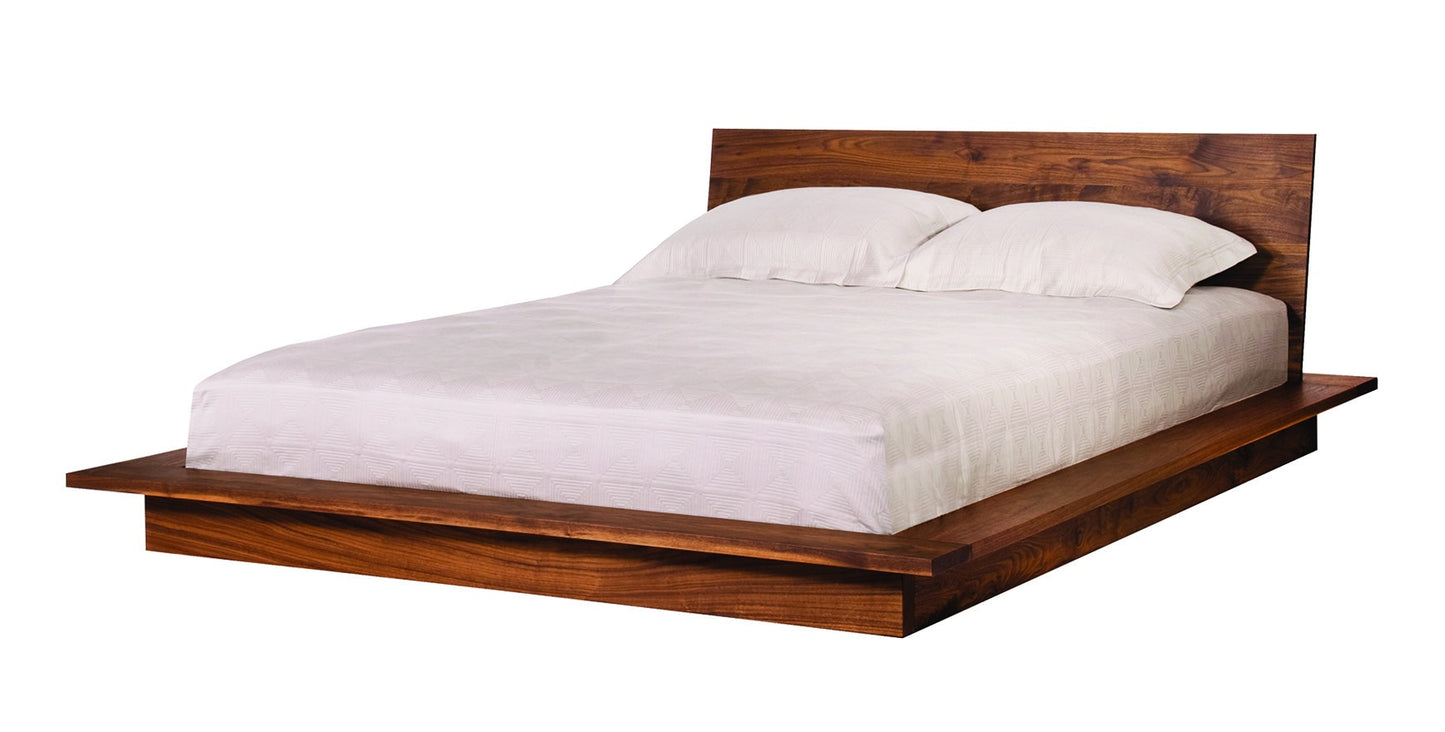 A modern platform bed with a dark Walnut wood frame and headboard, dressed in white bedding and pillows, shown against a plain white background.