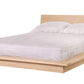 A modern platform bed with a light Maple wood frame and headboard, dressed in white bedding and two pillows, shown against a plain white background.