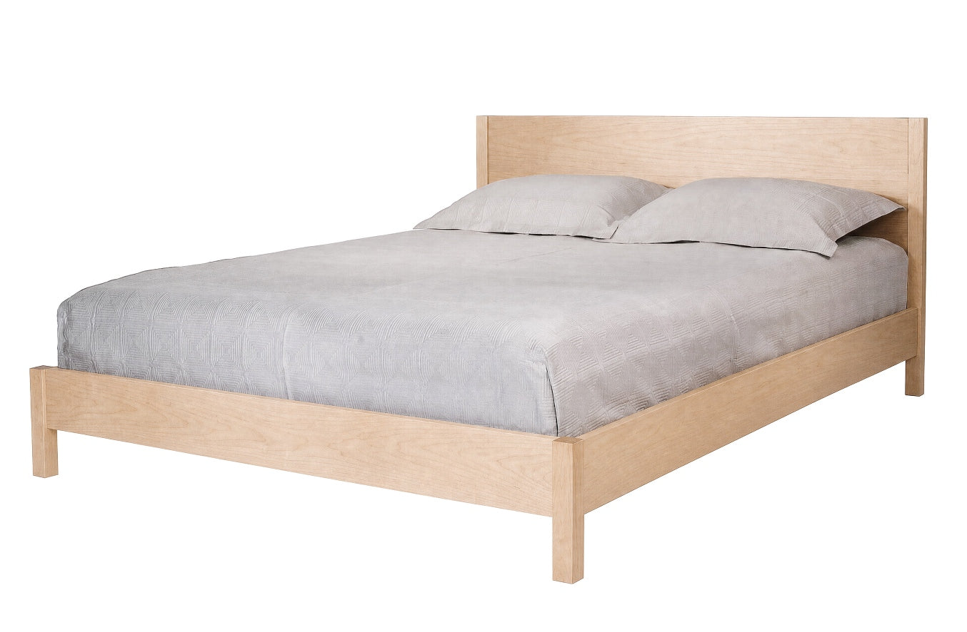 A light natural wood platform bed frame with a matching headboard, dressed in gray bedding and two gray pillows, shown against a plain white background.