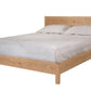 A light oak wood platform bed frame with a matching headboard, styled with light gray bedding and two pillows, shown against a plain white background.