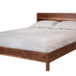 A dark Walnut wood platform bed frame with a matching headboard, styled with light gray bedding and two pillows, shown against a plain white background.
