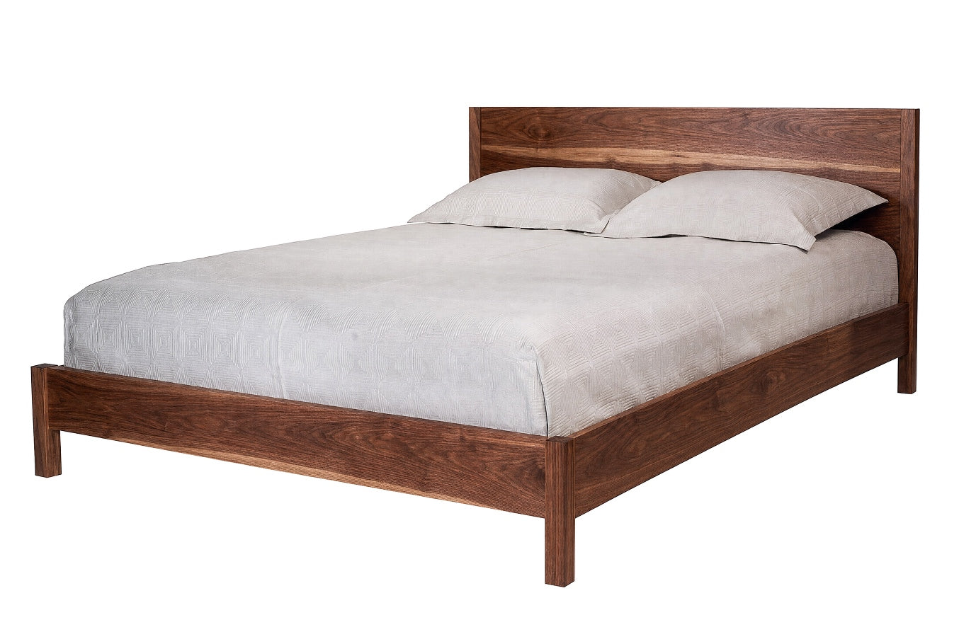 A dark Walnut wood platform bed frame with a matching headboard, styled with light gray bedding and two pillows, shown against a plain white background.