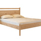 A light oak wood bed frame with a slatted headboard and footboard, shown with a mattress and two pillows on a plain white background.