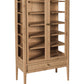 A tall, light oak wood display cabinet with two glass doors, multiple interior shelves, and a single drawer at the bottom, shown on a plain white background.