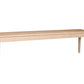 A long rectangular wooden bench with four legs, shown from a three-quarter angle on a solid white background.