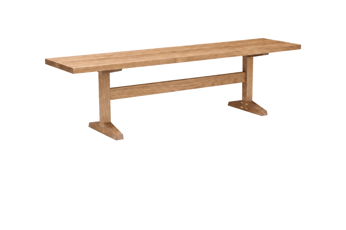 A light brown wooden bench with a rectangular seat and two angled support legs connected by a horizontal stretcher bar, shown on a plain white background.