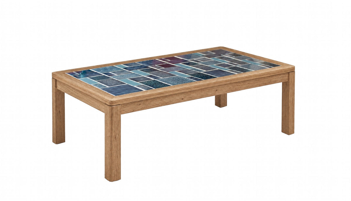 A rectangular wooden coffee table with a colorful mosaic tile top featuring shades of blue and teal, set against a plain white background.