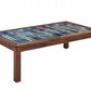 A rectangular wooden coffee table with a colorful mosaic tile top featuring shades of blue and teal, set against a plain white background.