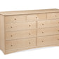 A wooden nine-drawer dresser with a light Maple finish and small round knobs, photographed on a plain white background.