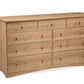 A wooden nine-drawer dresser with an Oak finish and small round knobs, photographed on a plain white background.