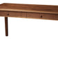 A medium brown wooden writing desk with two drawers and round knobs, shown on a plain white background.
