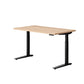 An electric height-adjustable desk with a light Maple wood grain top and black metal legs, shown on a solid white background.
