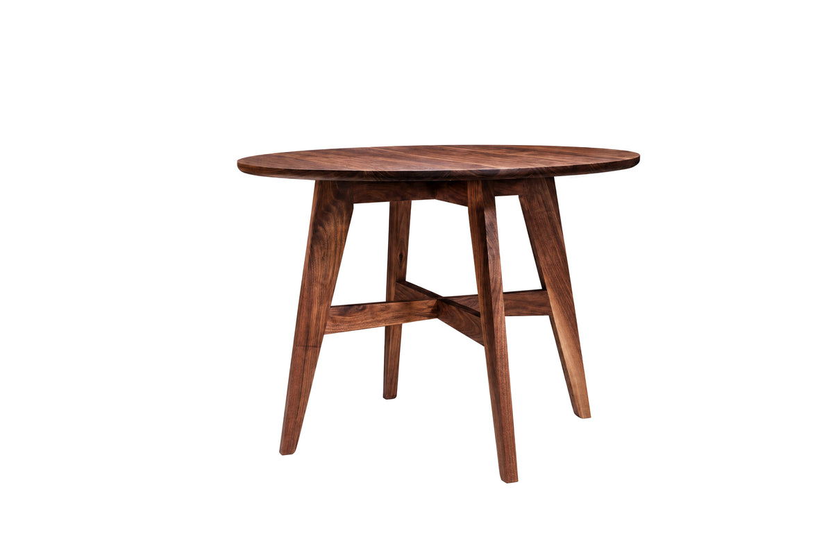 A round Walnut wooden dining table with angled splayed legs and a central stretcher bar, shown on a plain white background.