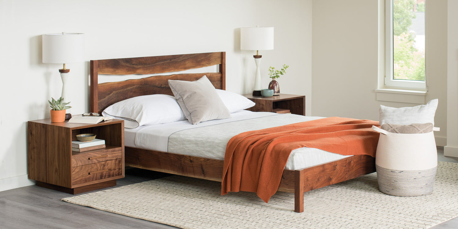 Wooden bed with orange blanket in a bedroom setting