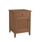 A small wooden nightstand with a single drawer and one cabinet door, finished in a warm medium brown wood tone with dark metal hardware, shown on a plain white background.