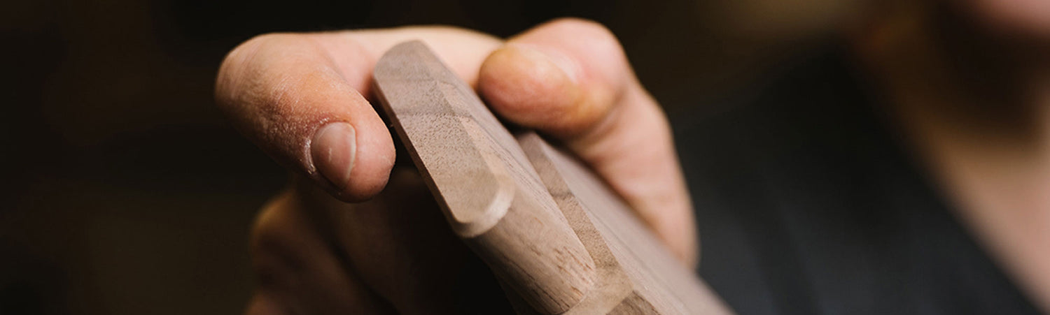 Close-up of a hand holding a wooden object with a blurred background