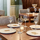 Dining table set with wine glasses, plates, and candles in a restaurant setting.
