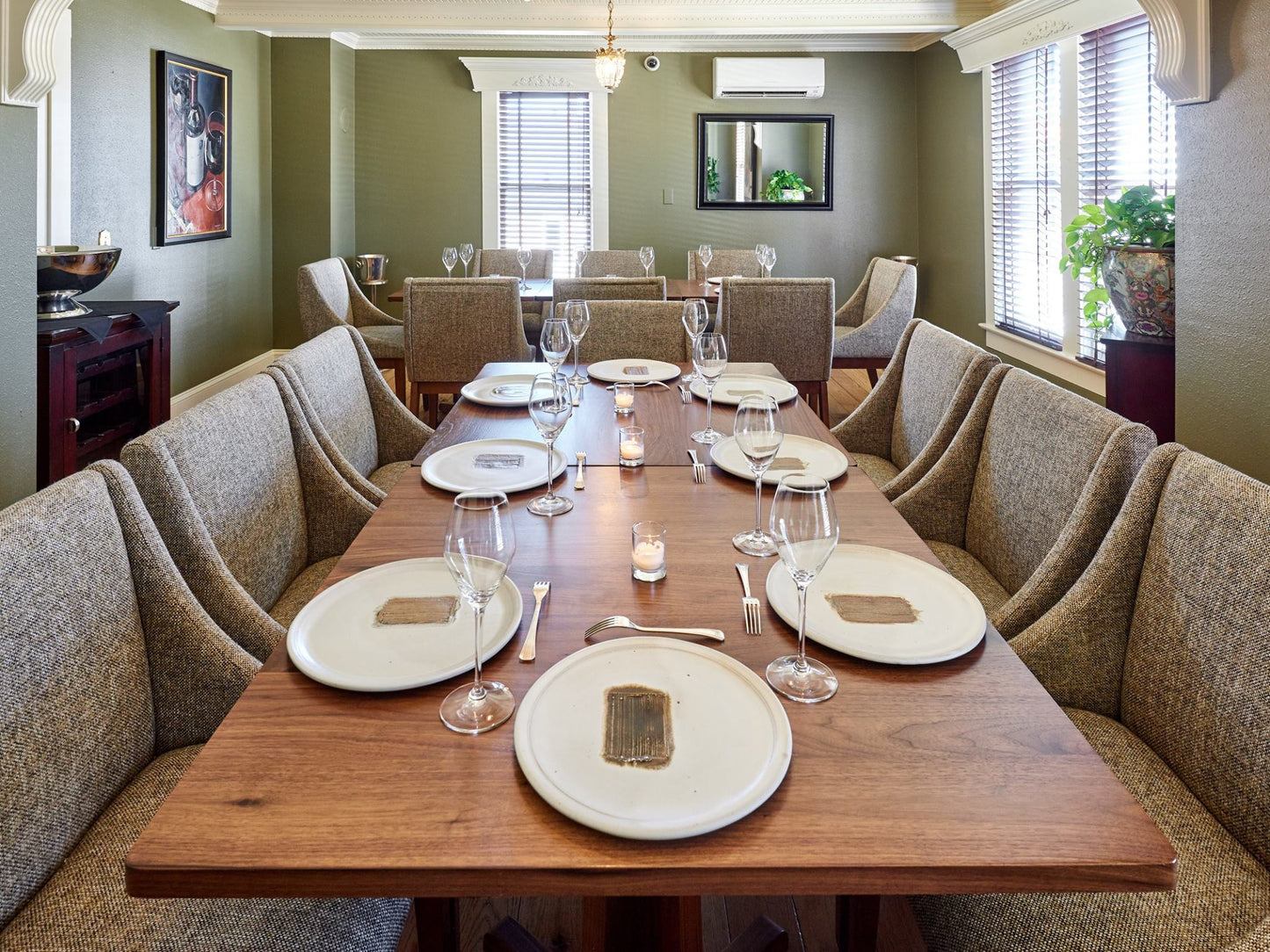 Dining room with a long wooden table set for a meal, surrounded by upholstered chairs.