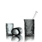 Set of three black glass tumblers with a straw on a white background