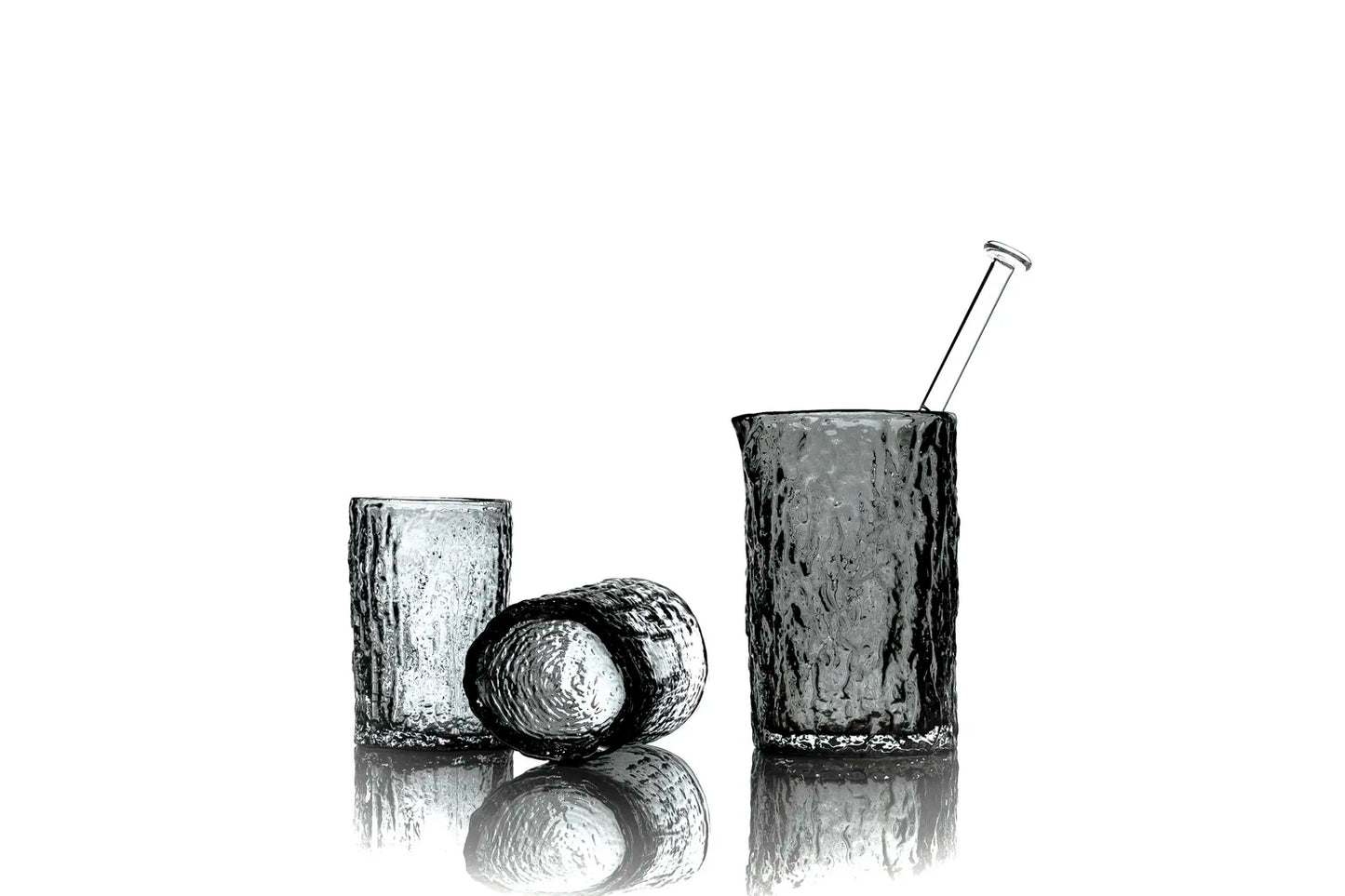 Set of three black glass tumblers with a straw on a white background