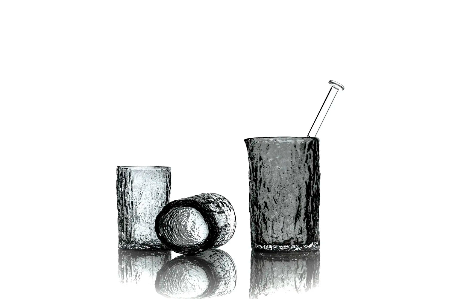 Set of three black glass tumblers with a straw on a white background
