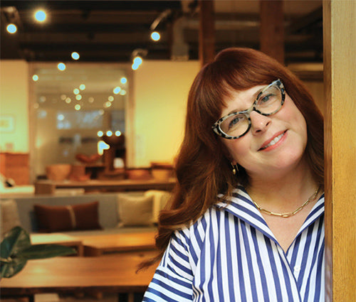 Woman with glasses and a striped shirt in a casual indoor setting